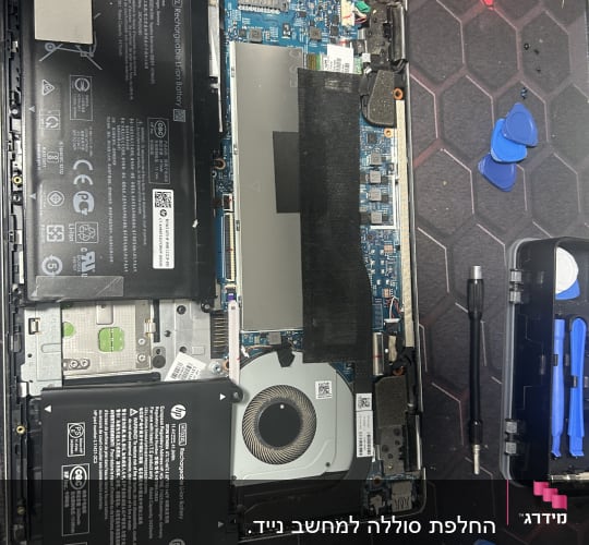 מחשב נייד פתוח עם סוללה, מאוורר וכלי עבודה